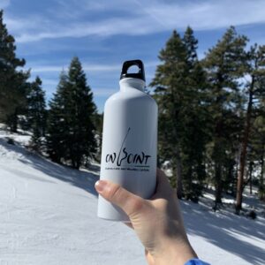 On Point water bottle being held in front of a snowy mountain slope